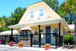 a dog's way inn exterior, yellow 2 story building with black fence and gate, daycare in myrtle beach